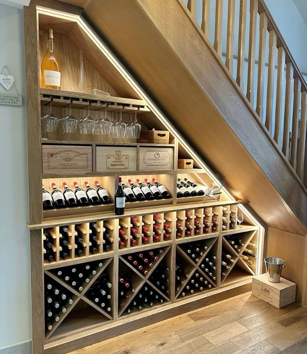 Wooden wine bar with integrated lighting built into the space under a staircase.