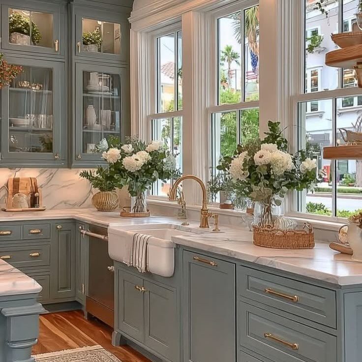 Grey farmhouse kitchen with white marble counters, apron sink, and gold fixtures.