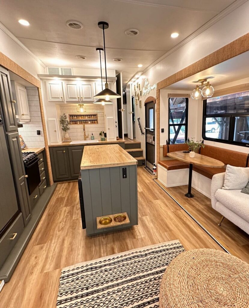 Remodeled fifth wheel interior with grey cabinetry, wooden island, and cozy dining nook.