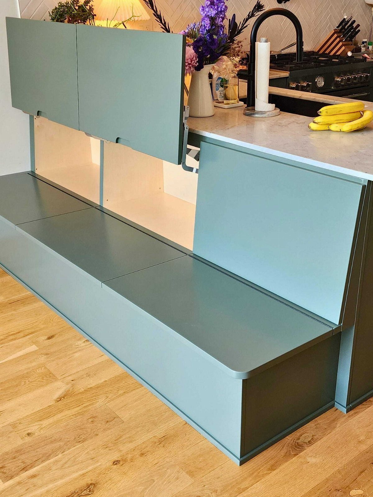 Light blue L-shaped banquette with lift-top seats revealing storage compartments in a kitchen.