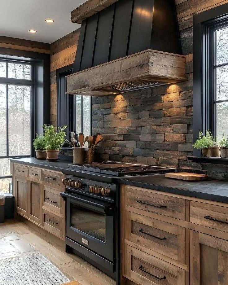 Rustic kitchen with reclaimed wood cabinets, black countertops, and a large black range hood.